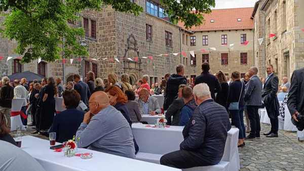 Menschen sitzen im Freien an gedeckten Tischen