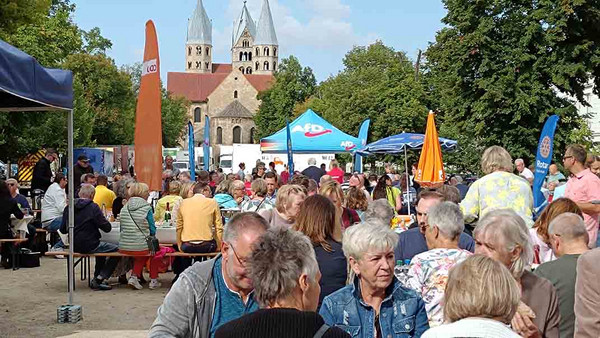 viele Menschen sitzen im Freien an Bänken.