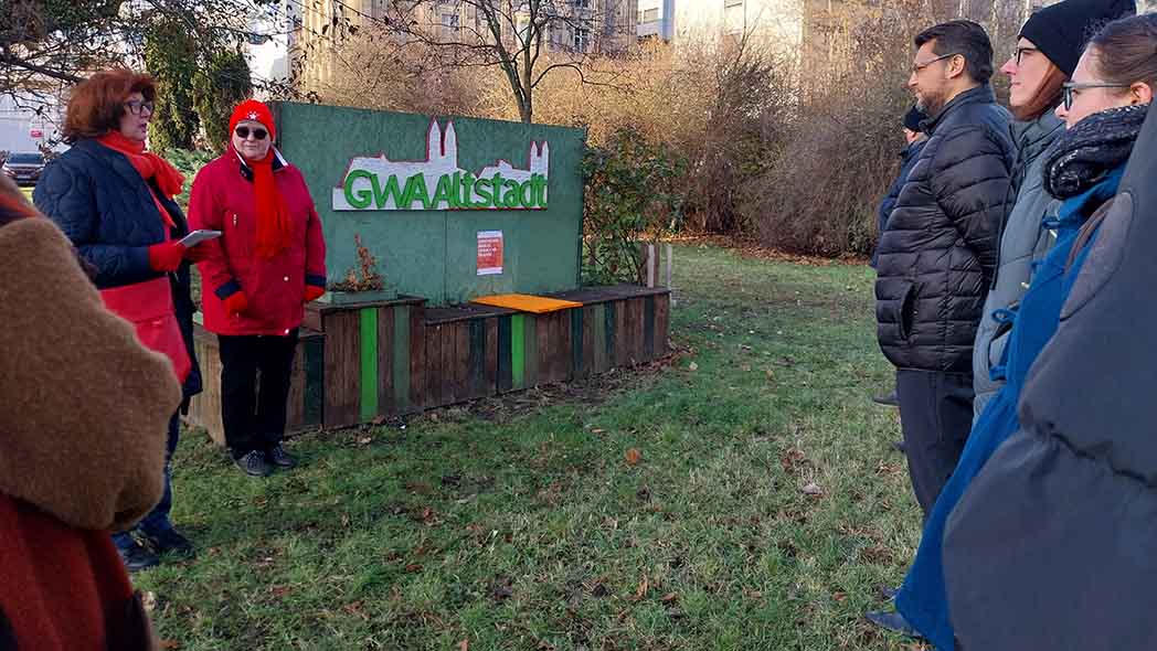 Menschen stehen vor einer Sitzbank mit orangem Brett