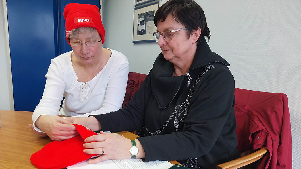 Zwei Frauen mit roten Mützen.