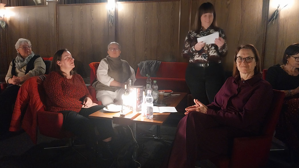 Fünf Frauen in dunklem Raum.